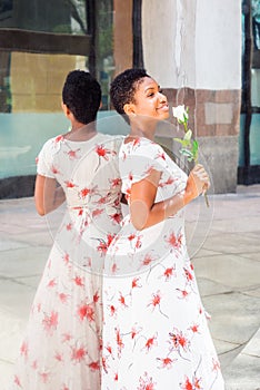 Young African American Woman holding a white rose, standing by mirror