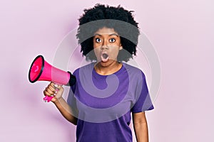Young african american woman shouting through megaphone scared and amazed with open mouth for surprise, disbelief face