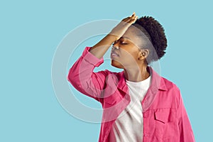 Young african american woman is showing facepalm gesture on blue background.