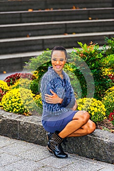 Young African American Woman sitting outdoors by garden, smiling