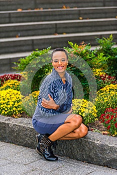 Young African American Woman sitting outdoors by garden, smiling