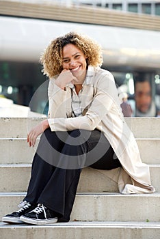 Young african american woman sitting on steps in city