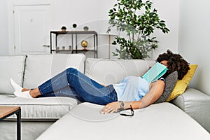 Young african american woman sleeping with book on face at home