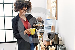 Young african american woman smiling confident pouring coffee at office