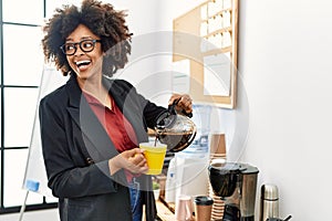 Young african american woman smiling confident pouring coffee at office