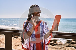 Young african american woman smiling happy having video call using touchpad at the beach