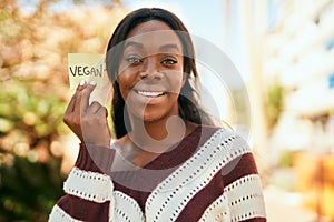 Young african american woman smiling happy holding reminder with vegan word at the park