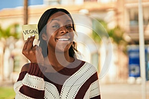 Young african american woman smiling happy holding reminder with vegan word at the park