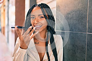 Young african american woman smiling happy sending voice message using smartphone at the city