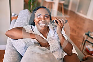 Young african american woman smiling happy sitting using smartphone at home