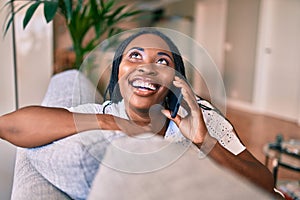 Young african american woman smiling happy sitting using smartphone at home