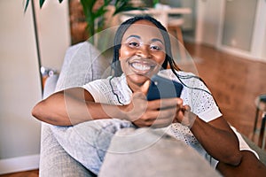 Young african american woman smiling happy sitting using smartphone at home