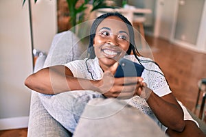 Young african american woman smiling happy sitting using smartphone at home