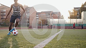 Young african american woman soccer player and training at city stadium while practicing dribbling with a ball