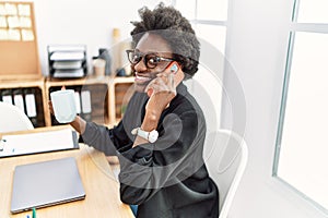 Young african american woman speaking on the phone drinking coffee at office