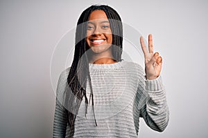 Young african american woman standing casual and cool over grey isolated background smiling with happy face winking at the camera