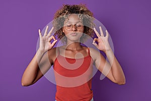 Young African American woman teen stands in yoga meditation pose in studio