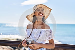 Young african american woman tourist smiling confident using camera at seaside