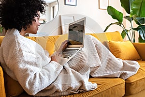 Young african american woman using laptop computer at home sitting on the sofa.