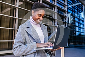 Young African American woman using laptop on street