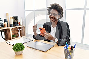 Young african american woman using smartphone drinking coffee at office