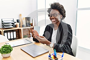 Young african american woman using smartphone drinking coffee at office