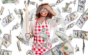 Young african american woman wearing apron holding rolling pin stressed and frustrated with hand on head, surprised and angry face