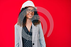 Young african american woman wearing architect hardhat looking to side, relax profile pose with natural face and confident smile