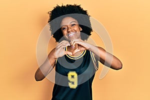 Young african american woman wearing basketball uniform smiling in love doing heart symbol shape with hands