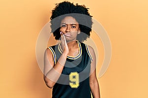 Young african american woman wearing basketball uniform touching mouth with hand with painful expression because of toothache or