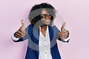 Young african american woman wearing business clothes and glasses approving doing positive gesture with hand, thumbs up smiling