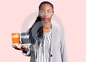 Young african american woman wearing business clothes holding take away cup of coffee thinking attitude and sober expression