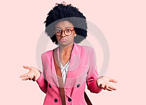 Young african american woman wearing business clothes and leather bag clueless and confused expression with arms and hands raised