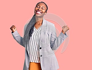 Young african american woman wearing business clothes very happy and excited doing winner gesture with arms raised, smiling and