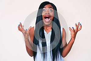 Young african american woman wearing casual clothes crazy and mad shouting and yelling with aggressive expression and arms raised