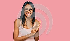 Young african american woman wearing casual clothes and glasses clapping and applauding happy and joyful, smiling proud hands