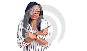 Young african american woman wearing casual clothes and glasses pointing to both sides with fingers, different direction disagree