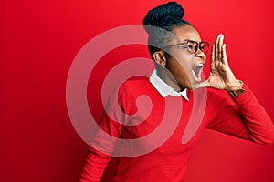 Young african american woman wearing casual clothes and glasses shouting and screaming loud to side with hand on mouth