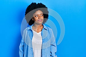 Young african american woman wearing casual clothes smiling looking to the side and staring away thinking
