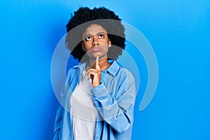 Young african american woman wearing casual clothes thinking concentrated about doubt with finger on chin and looking up wondering