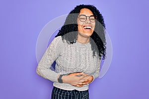 Young african american woman wearing casual sweater and glasses over purple background smiling and laughing hard out loud because