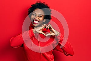 Young african american woman wearing casual sweatshirt smiling in love doing heart symbol shape with hands