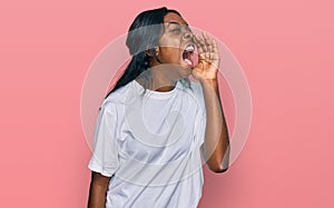 Young african american woman wearing casual white t shirt shouting and screaming loud to side with hand on mouth