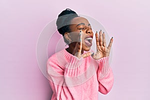 Young african american woman wearing casual winter sweater shouting angry out loud with hands over mouth