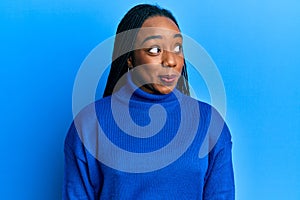 Young african american woman wearing casual winter sweater smiling looking to the side and staring away thinking