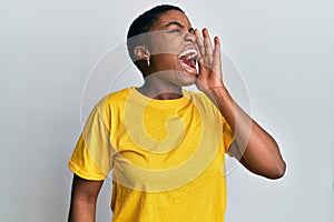 Young african american woman wearing casual yellow t shirt shouting and screaming loud to side with hand on mouth