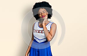 Young african american woman wearing cheerleader uniform touching mouth with hand with painful expression because of toothache or