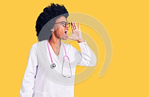 Young african american woman wearing doctor coat and stethoscope shouting and screaming loud to side with hand on mouth