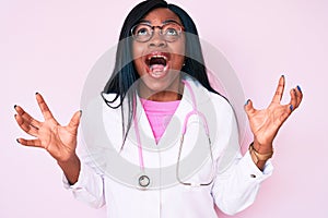 Young african american woman wearing doctor stethoscope crazy and mad shouting and yelling with aggressive expression and arms