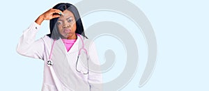Young african american woman wearing doctor stethoscope worried and stressed about a problem with hand on forehead, nervous and